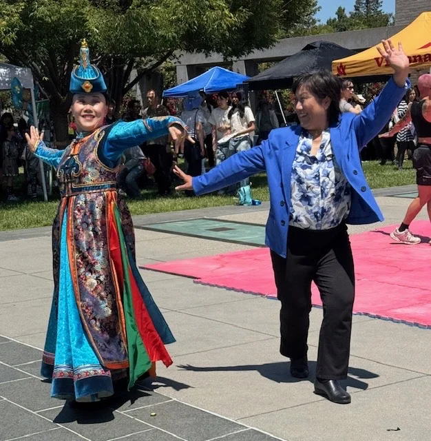 Liang Chao joining a cultural dance at an outdoor community celebration