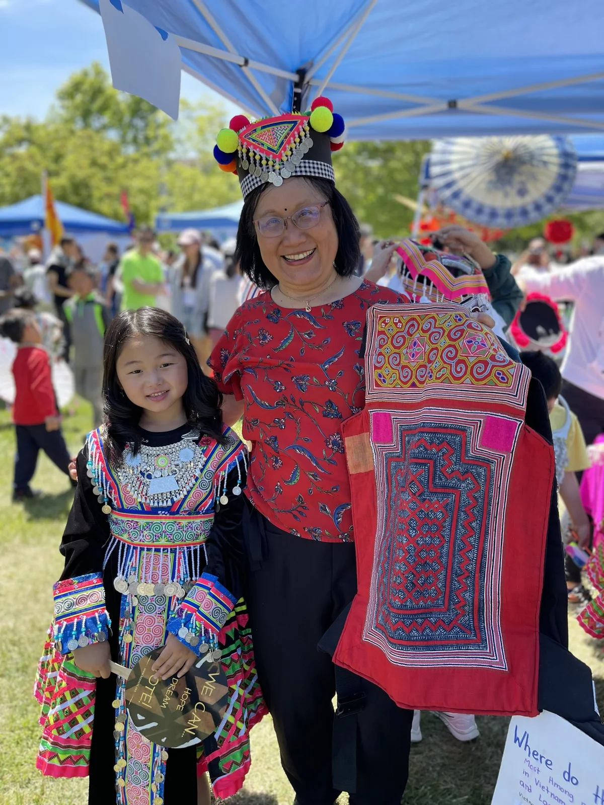 Liang Chao and a child displaying traditional clothing at a cultural festival